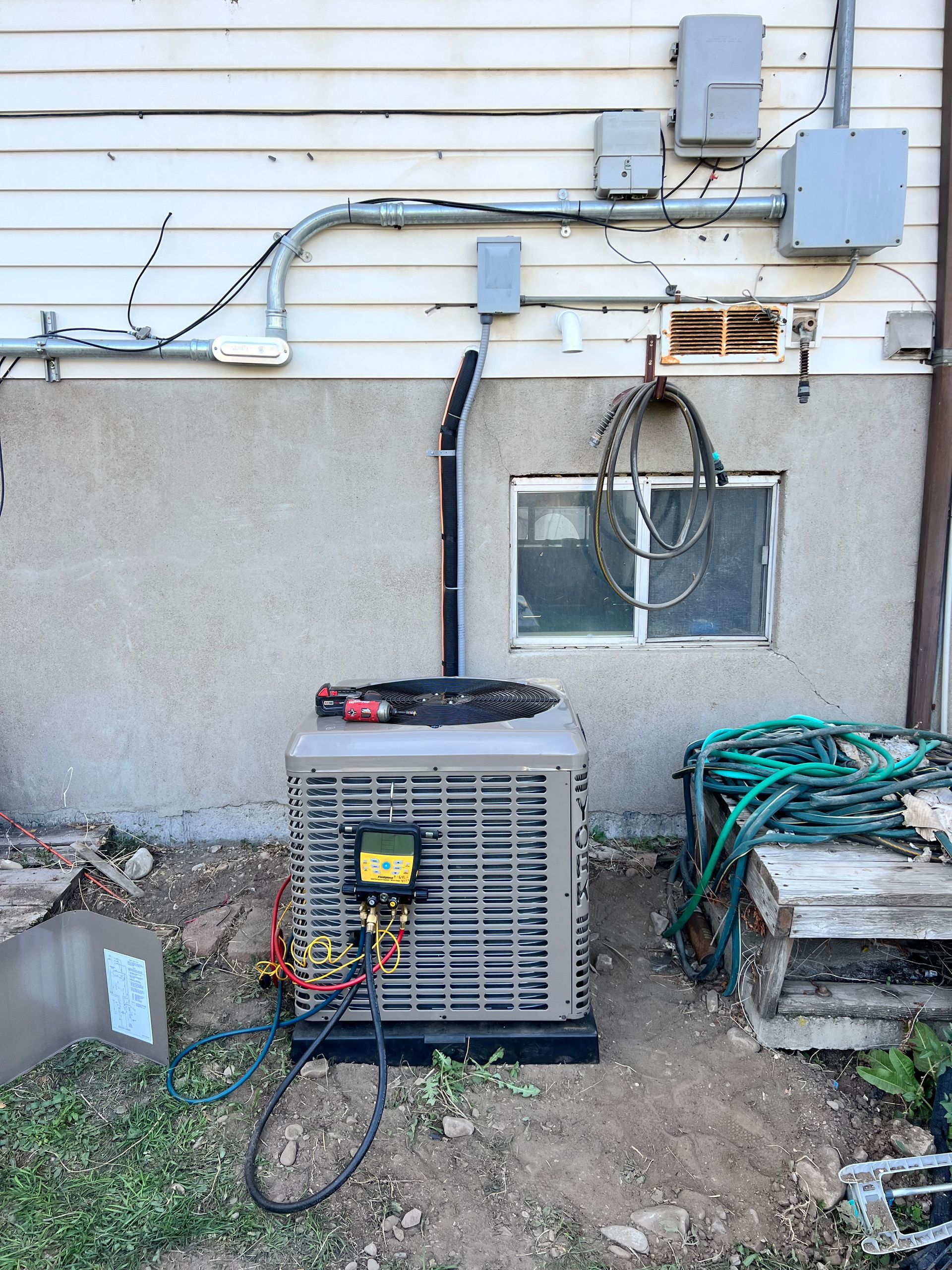 HVAC unit installed outdoors, connected to electrical conduit on a building's exterior.