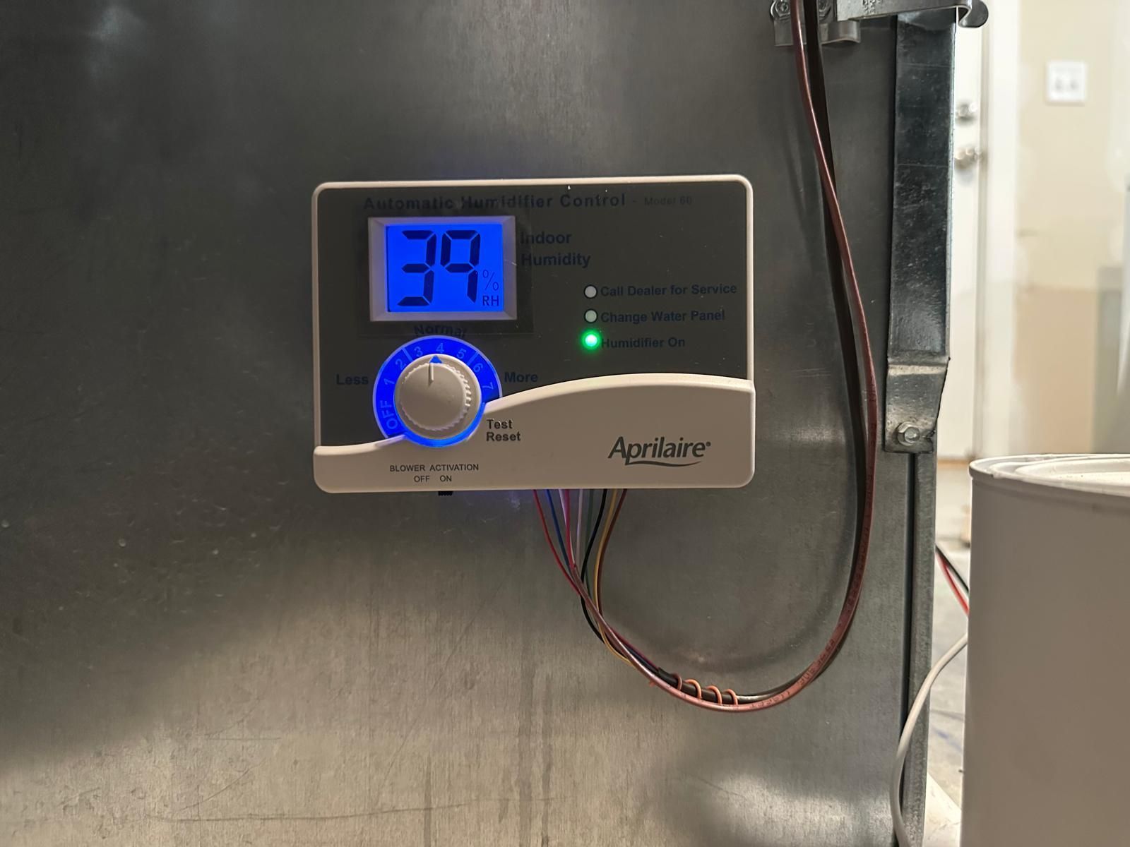 A digital humidifier control panel mounted on a metal surface, showing a reading of 39 and a green indicator light.