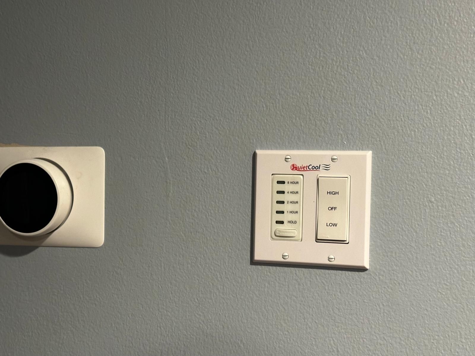 controller on the wall next to a thermostat for a whole house fan