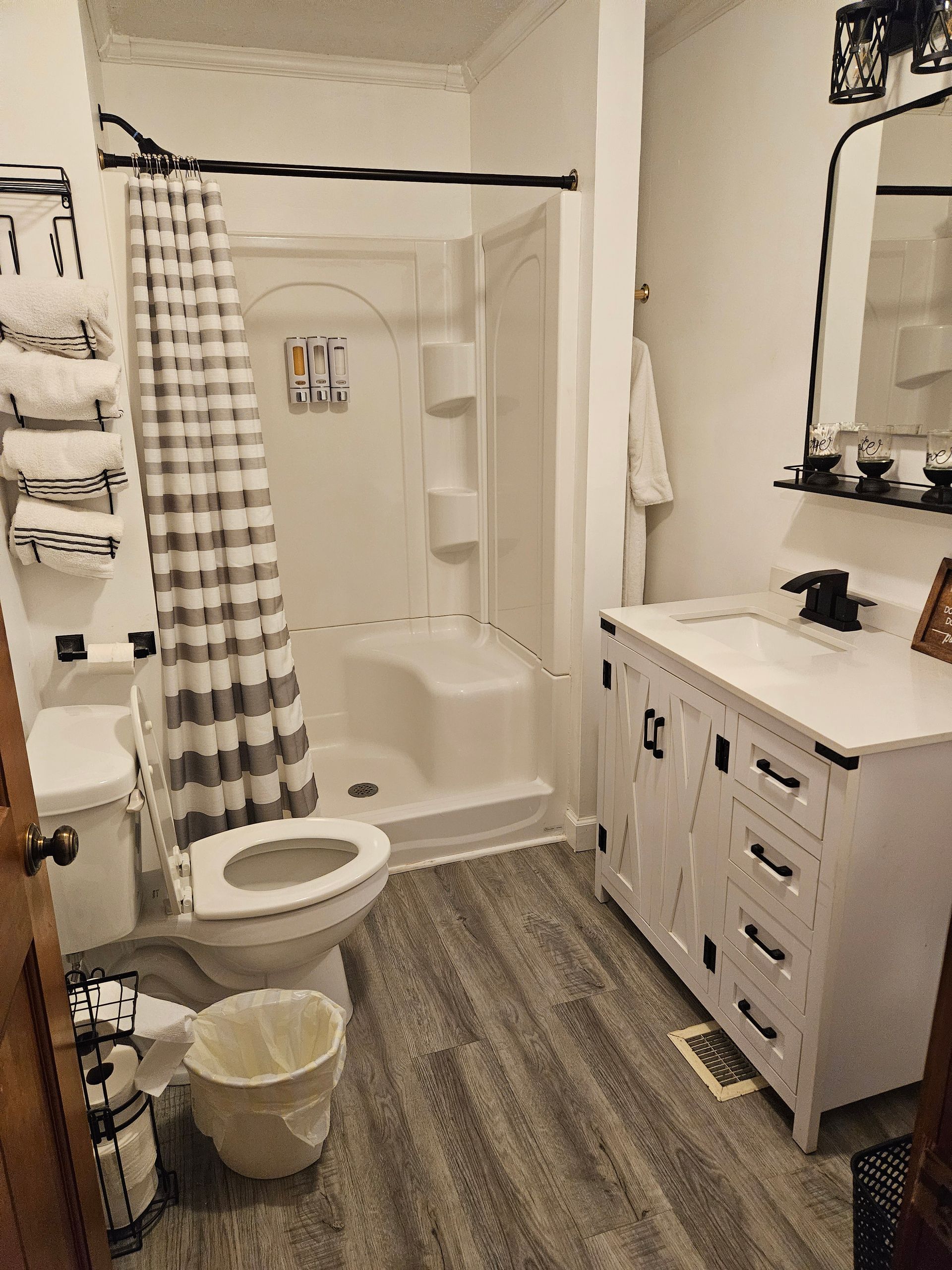 A bathroom with a toilet , sink , mirror and shower.