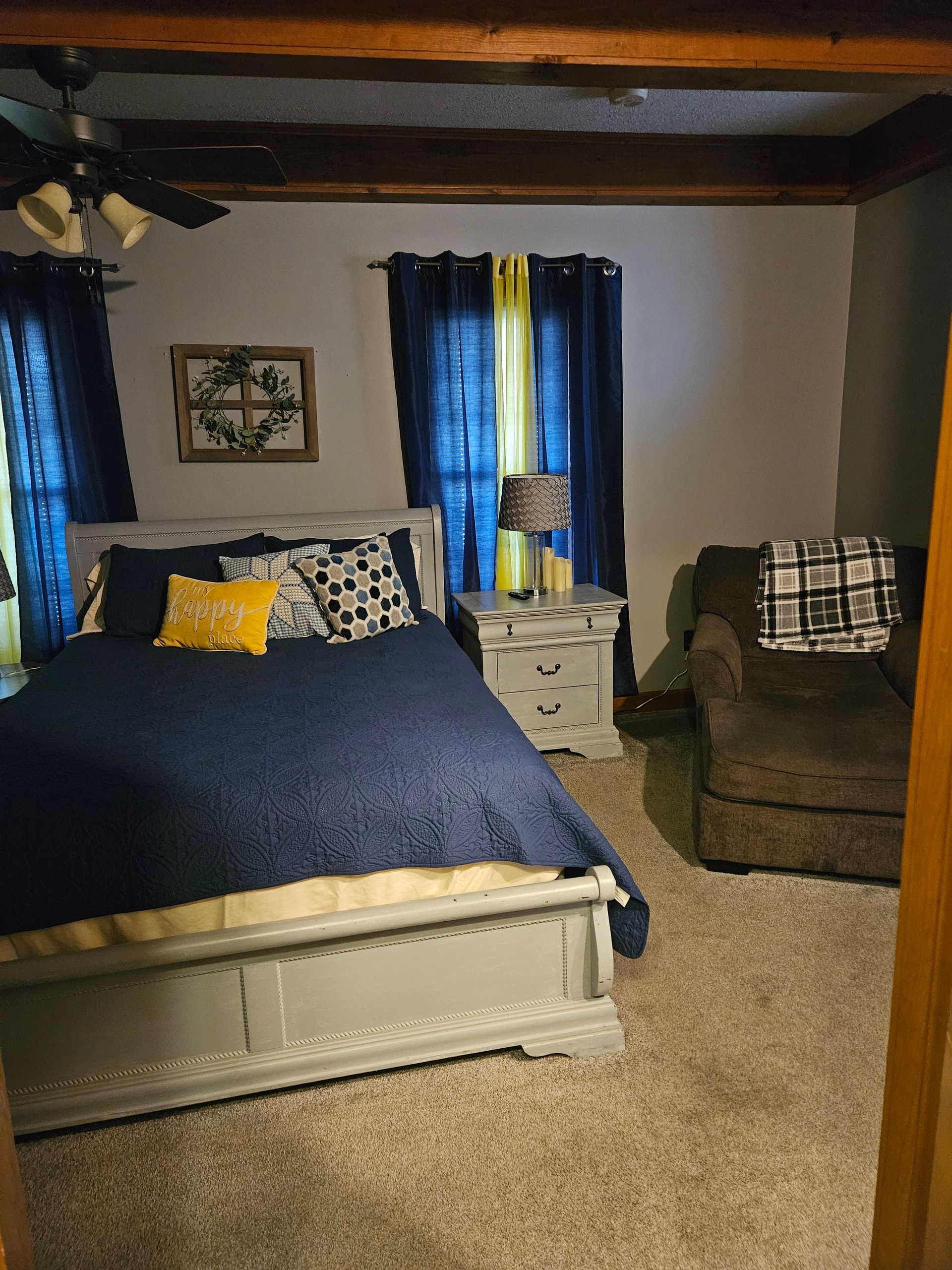 A bedroom with a bed , nightstand , chair and window.