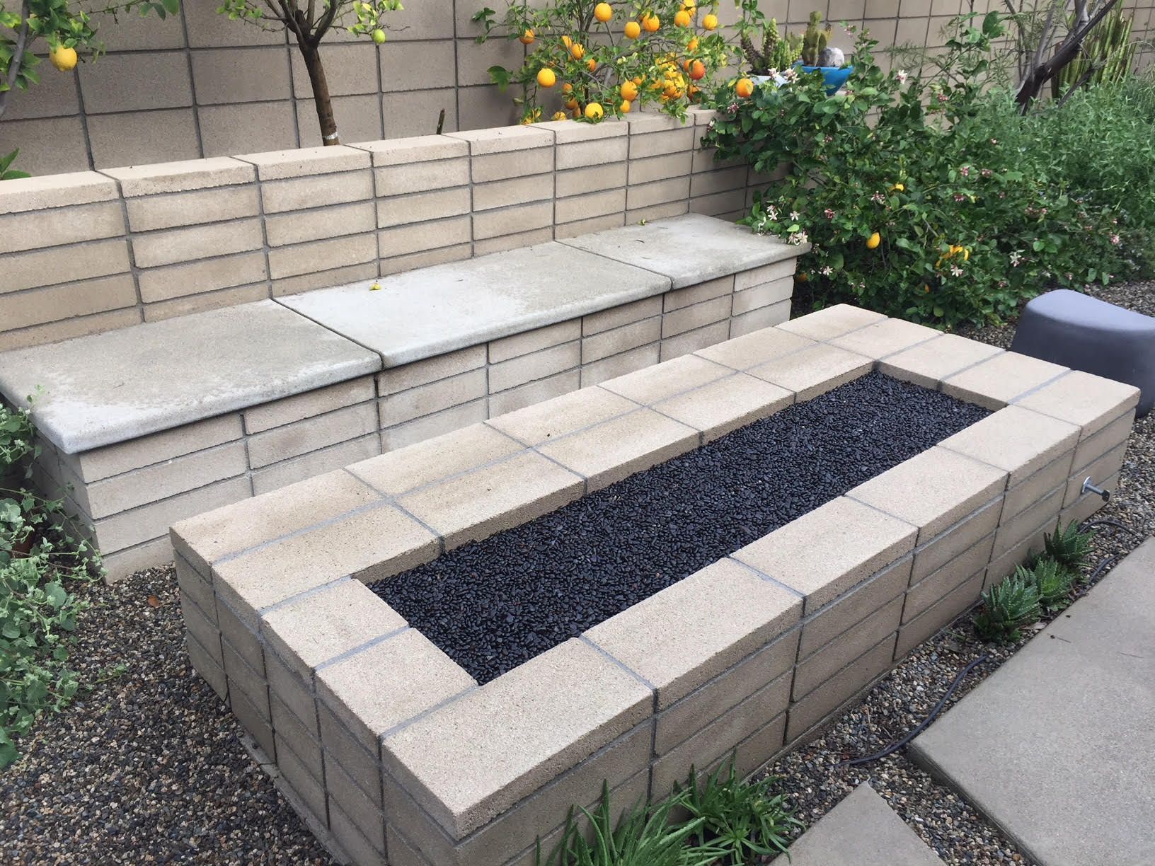 Tiered concrete planter boxes with black gravel in a garden courtyard