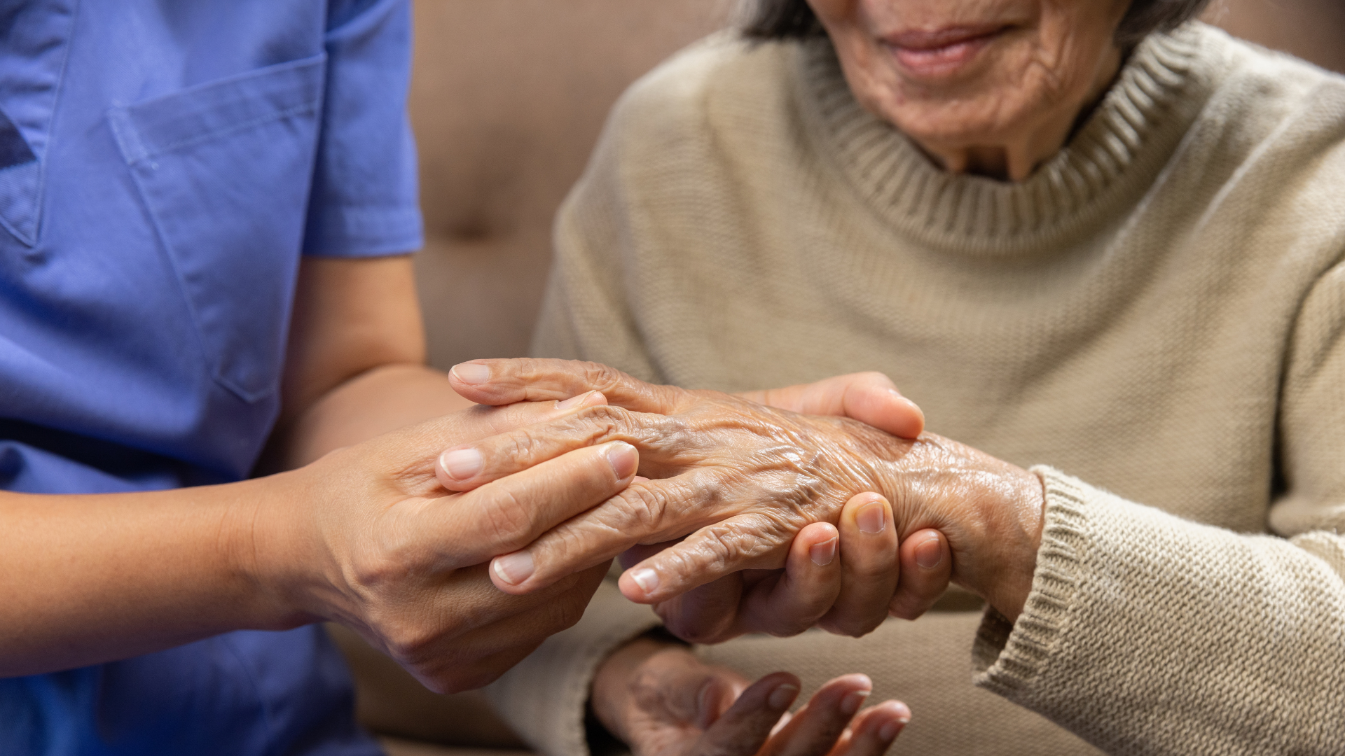 A nurse is holding the hand of an elderly woman.
