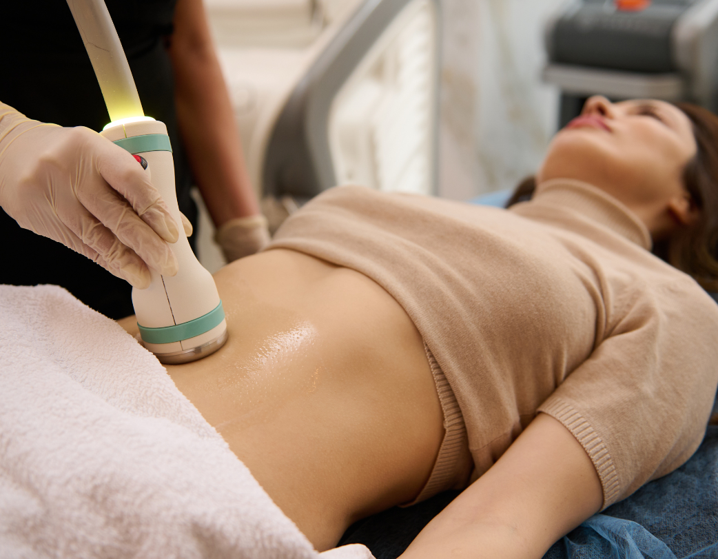 A woman is laying on a bed getting an ultrasound on her stomach.
