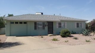 Single-story house with a light green garage and desert landscaping in front