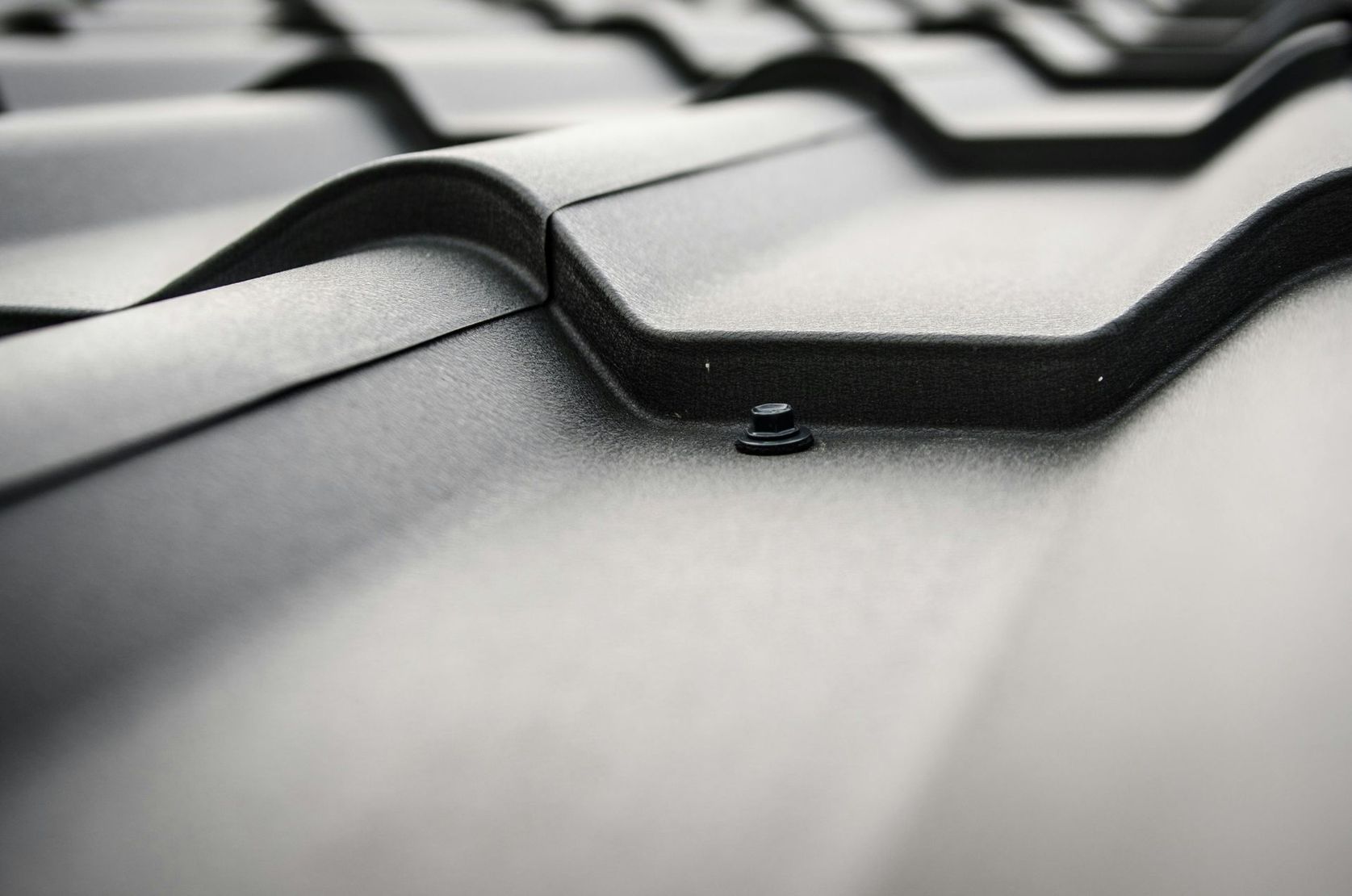 Close-up of black asphalt roof shingles with a ridge vent and textured surface