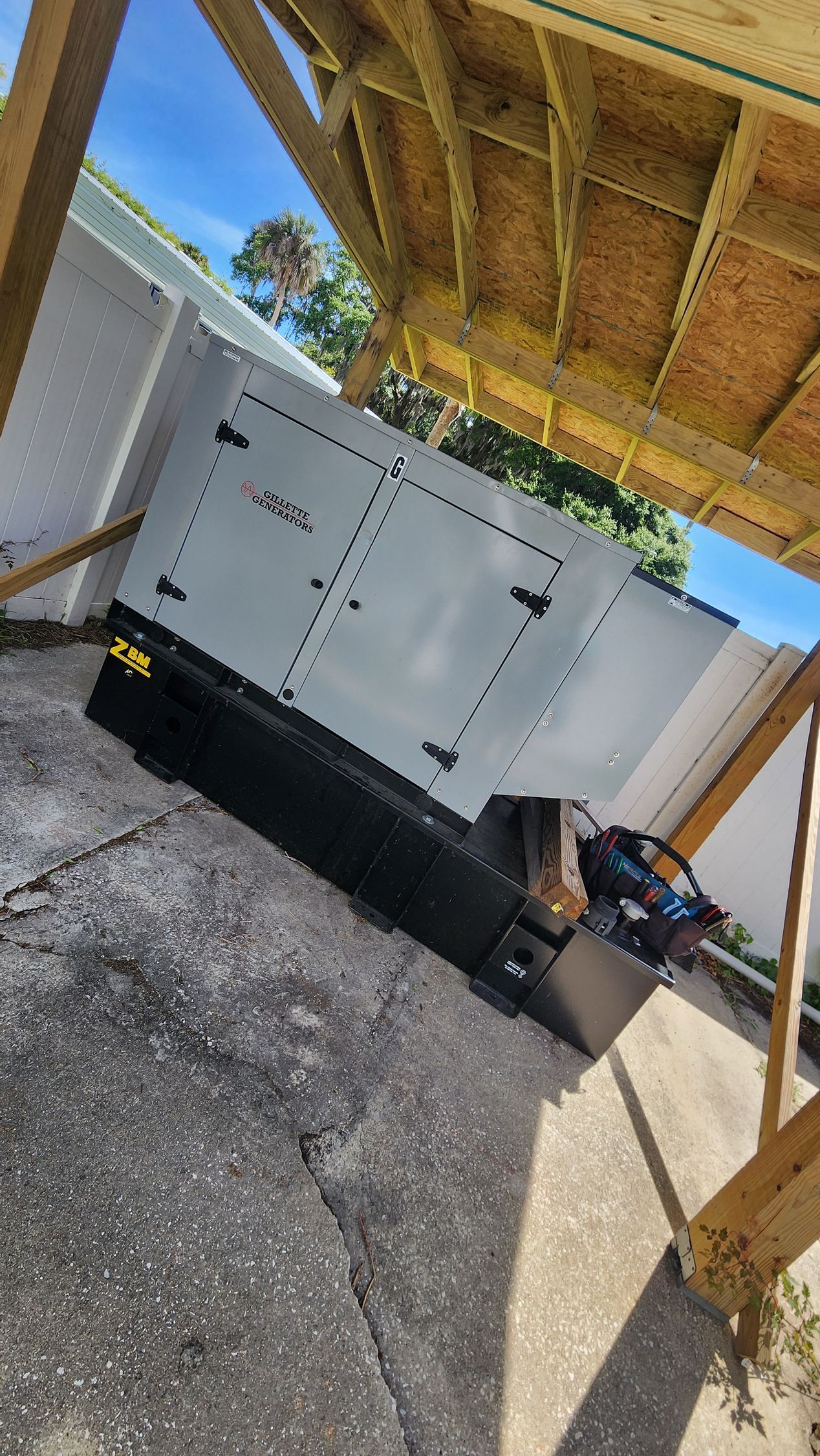 Gray generator with open doors, under a wooden structure, outdoors. Gray generator with open doors, under a wooden structure, outdoors.