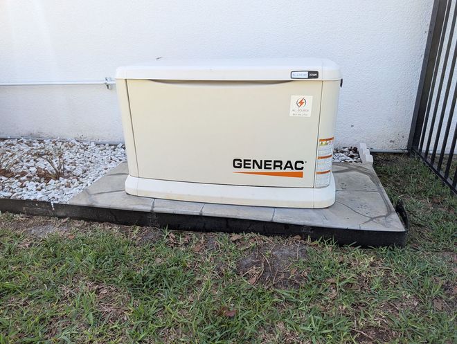 Man starting a red generator next to a white RV, person looks out the door, sunny outdoor setting.