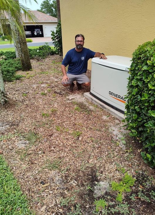 Man stands next to a Generac generator installed near a house window, outdoors on a concrete pad.