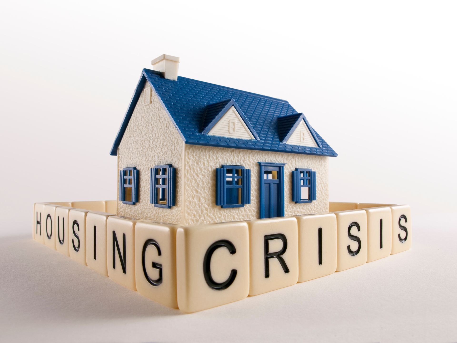 Toy house on blocks spelling “HOUSING CRISIS”