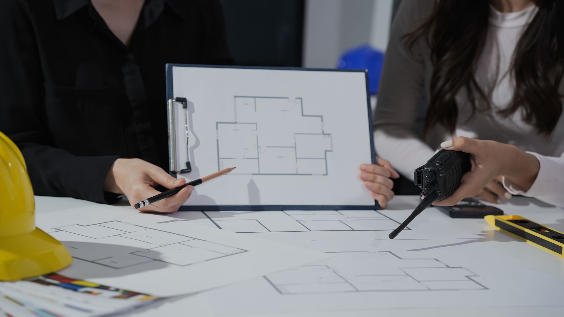 People in hard hats reviewing architectural blueprints at a construction table