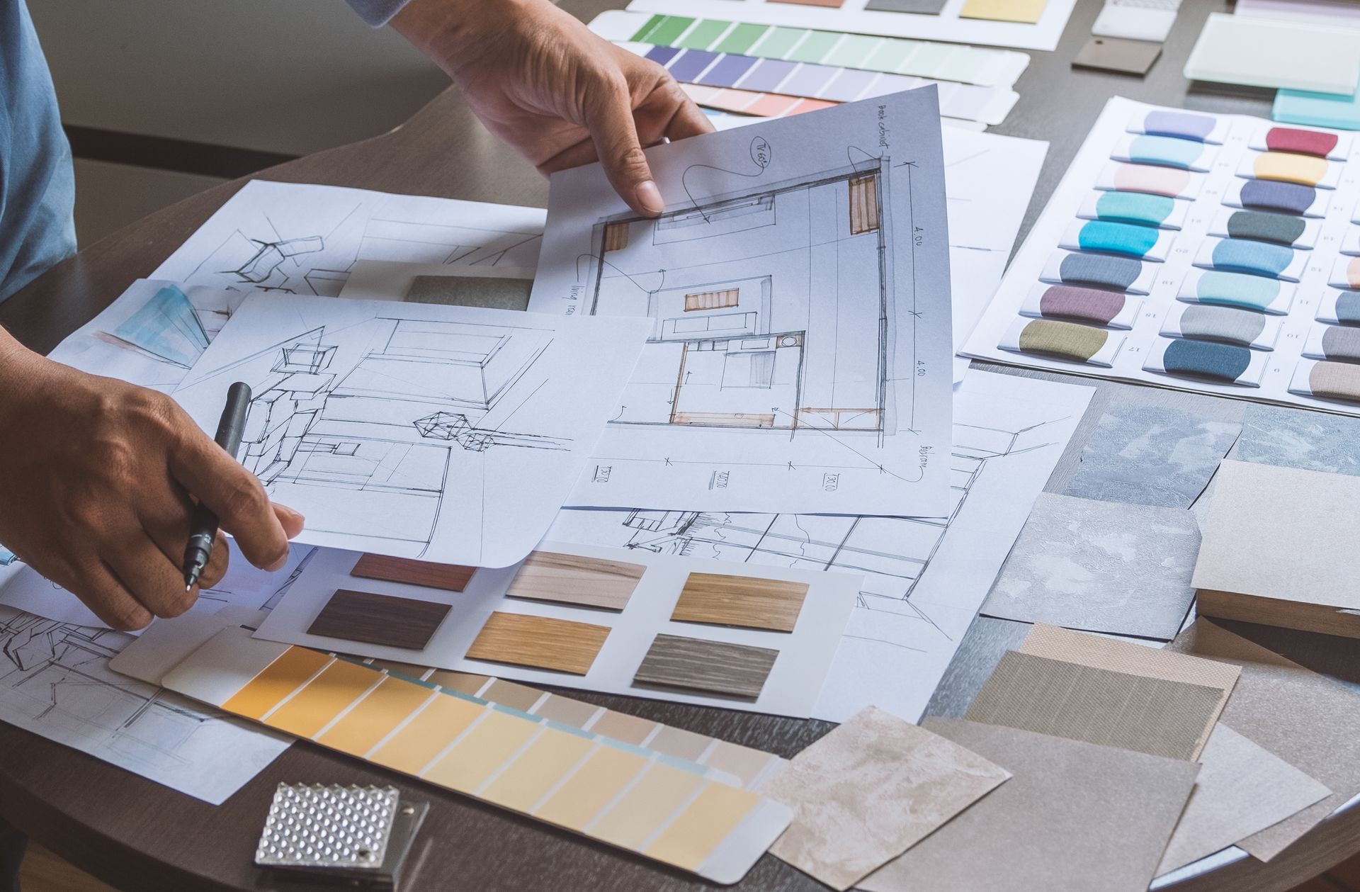 Hands arranging architectural plans and color swatches on a worktable Hands arranging architectural plans and color swatches on a worktable