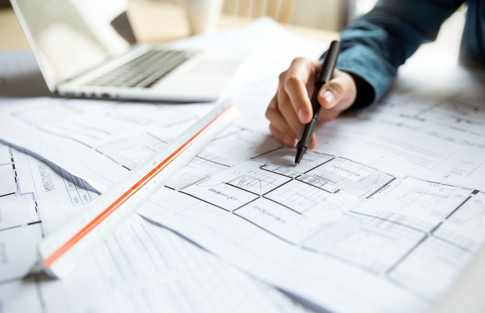 Hand drawing on architectural blueprints with a pen on a desk Hand drawing on architectural blueprints with a pen on a desk