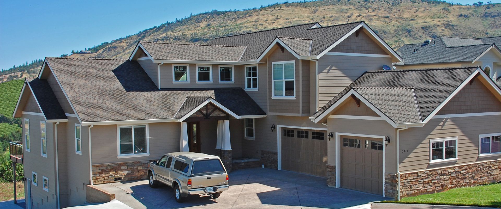 Large modern beige house with stone accents and a car parked in the driveway Large modern beige house with stone accents and a car parked in the driveway