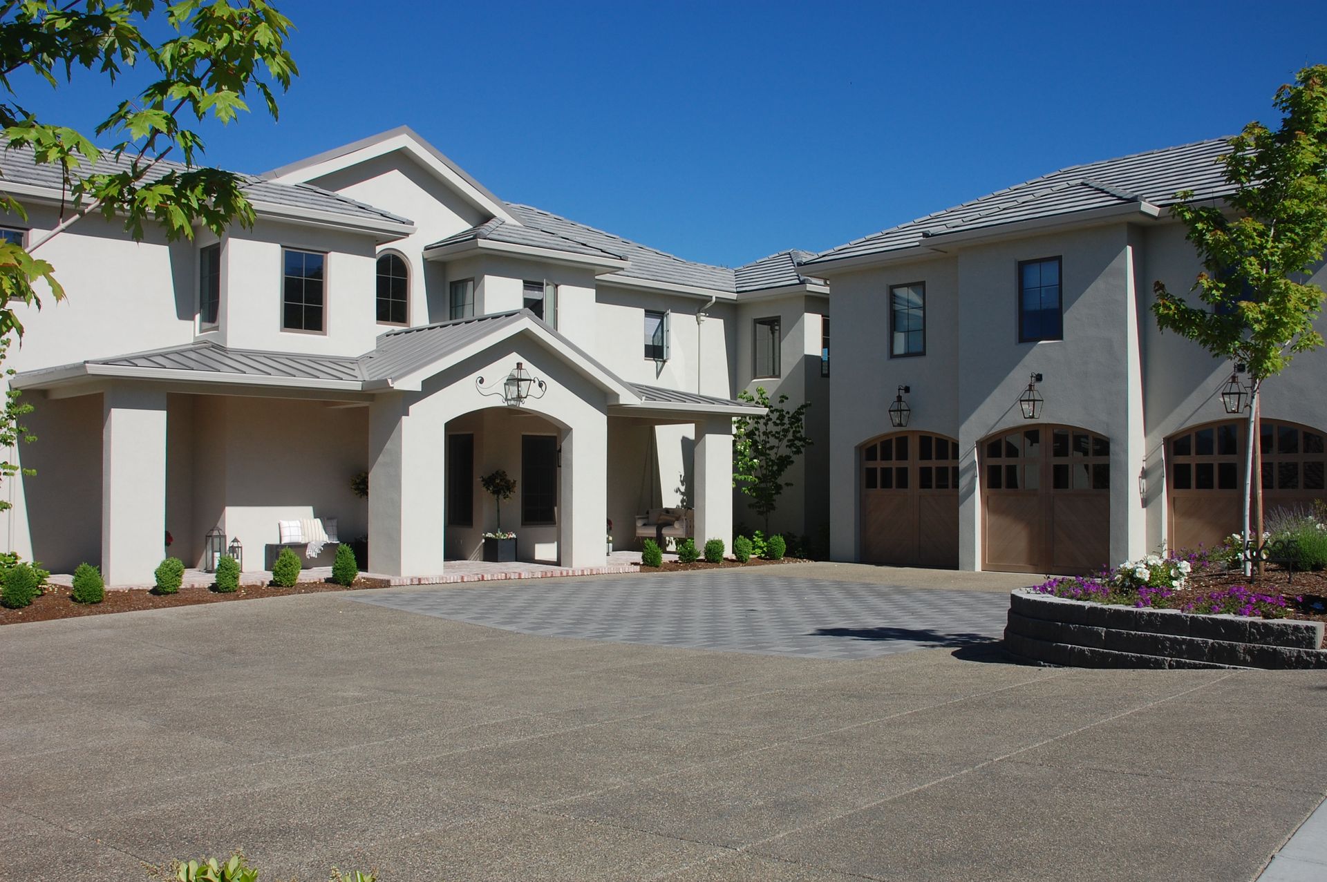 Large white two-story house with a tiled roof and arched entryway, viewed from the driveway.