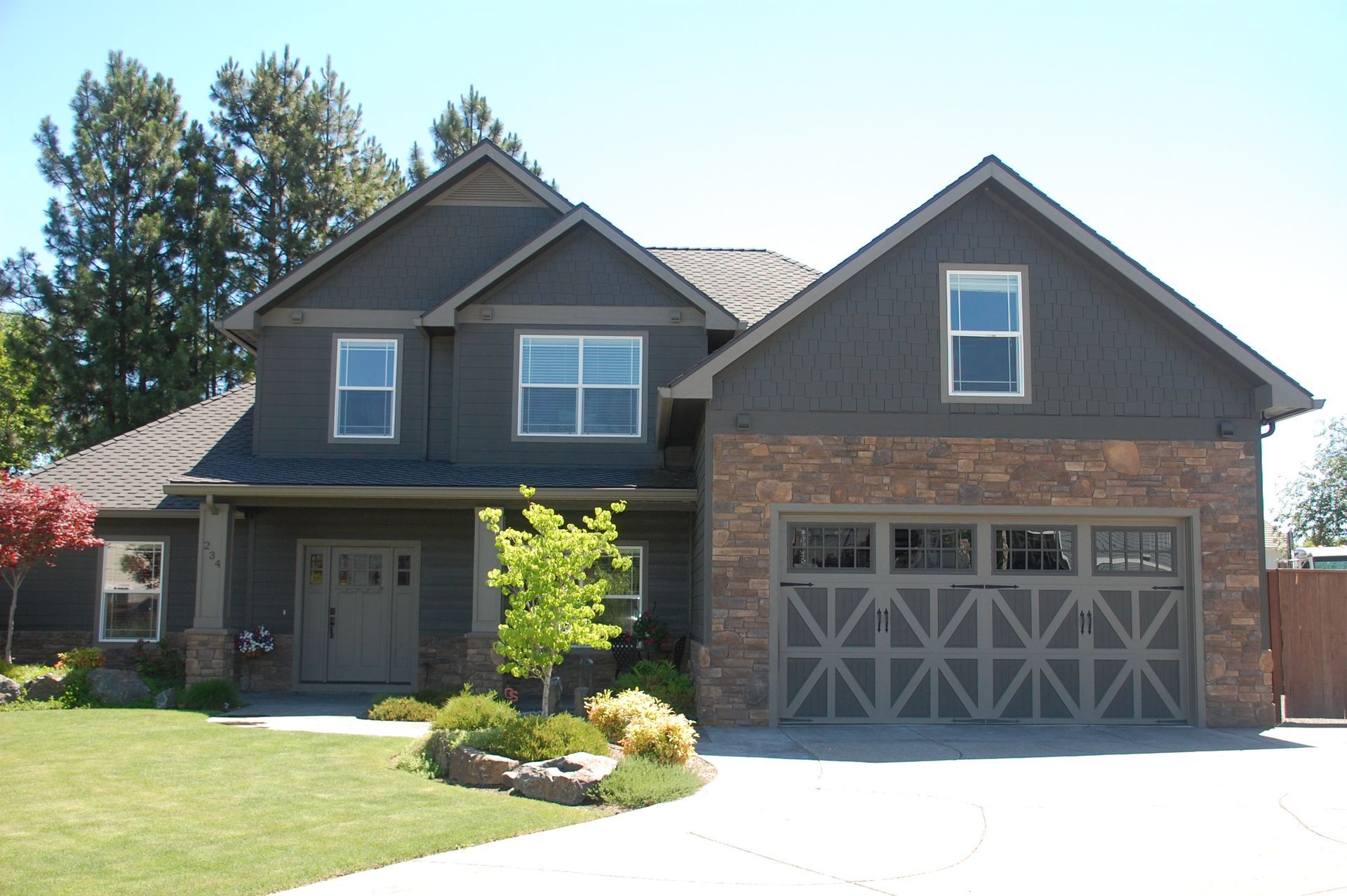 Two-story gray and brick suburban house with a double garage and a front lawn