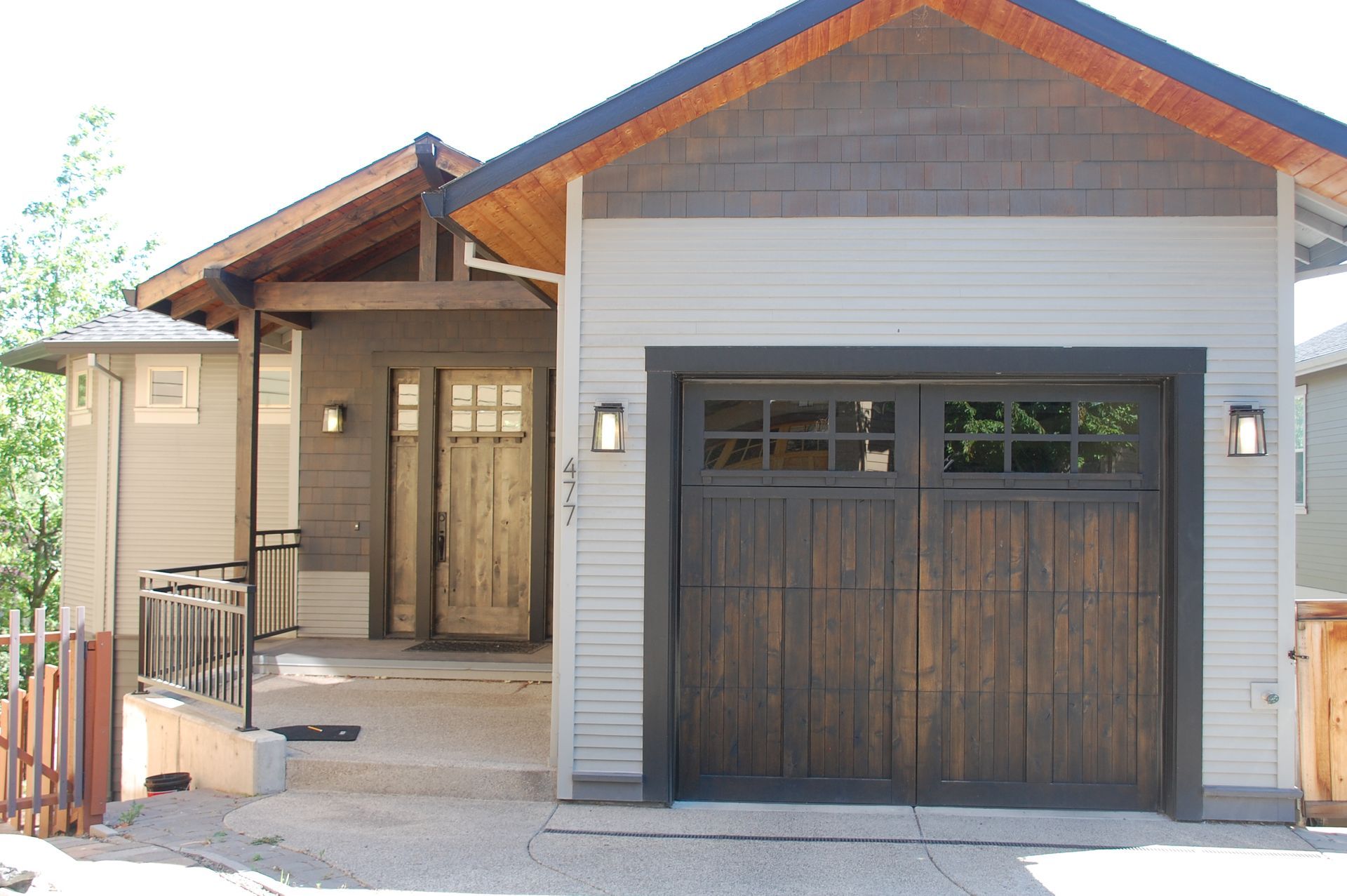 Front view of a modern house with a brown garage door, wood accents, and a covered entryway