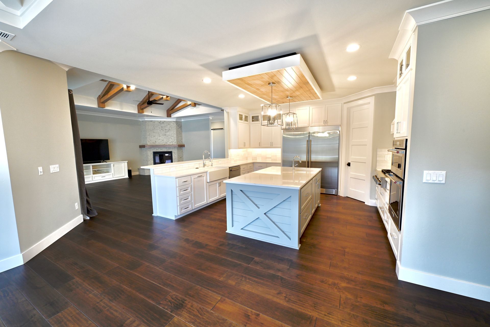 Bright modern kitchen with white cabinets, dark wood floors, island, and stainless steel appliances