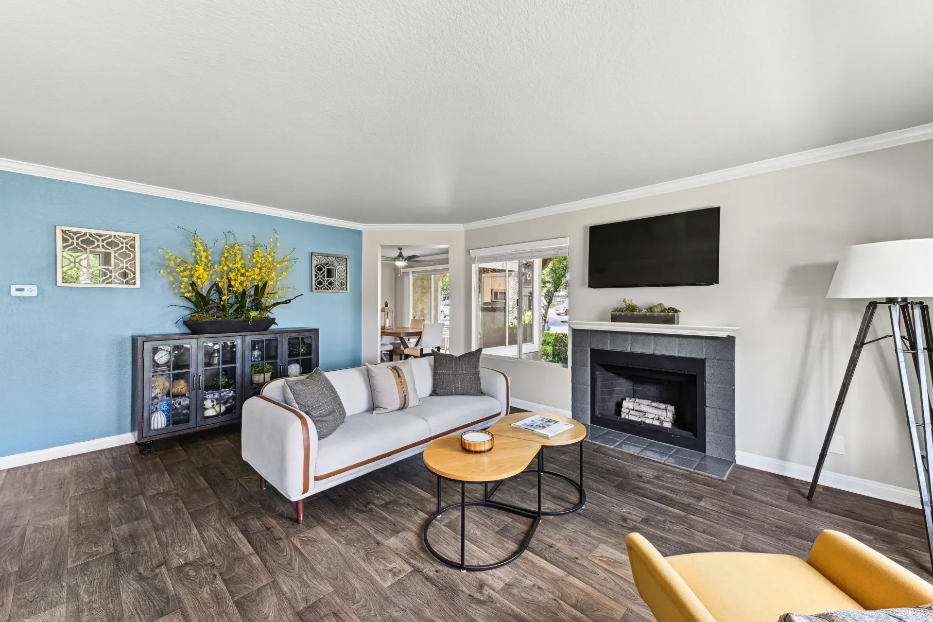 Living room in an apartment with a blue accent wall, sofa, fireplace, TV, and coffee tables.