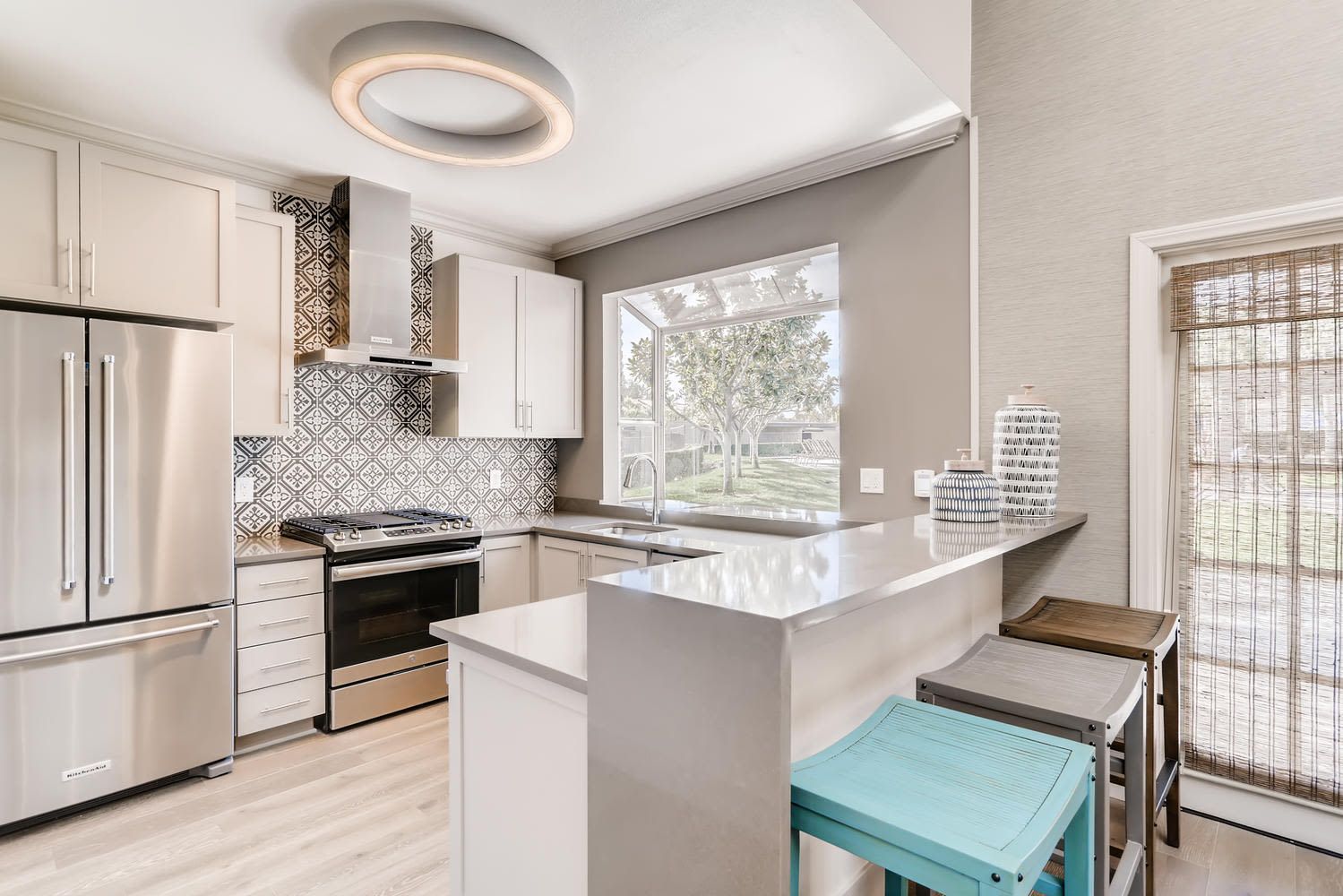 Modern kitchen with stainless steel appliances, white cabinets, and a patterned backsplash.