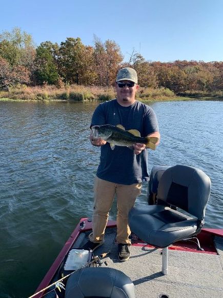 A man is standing on a boat holding a large fish.