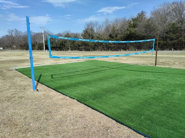 A volleyball net is sitting on top of a lush green field.