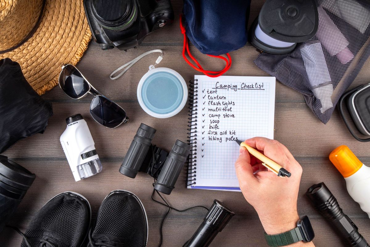 A person is writing in a notebook surrounded by various items.