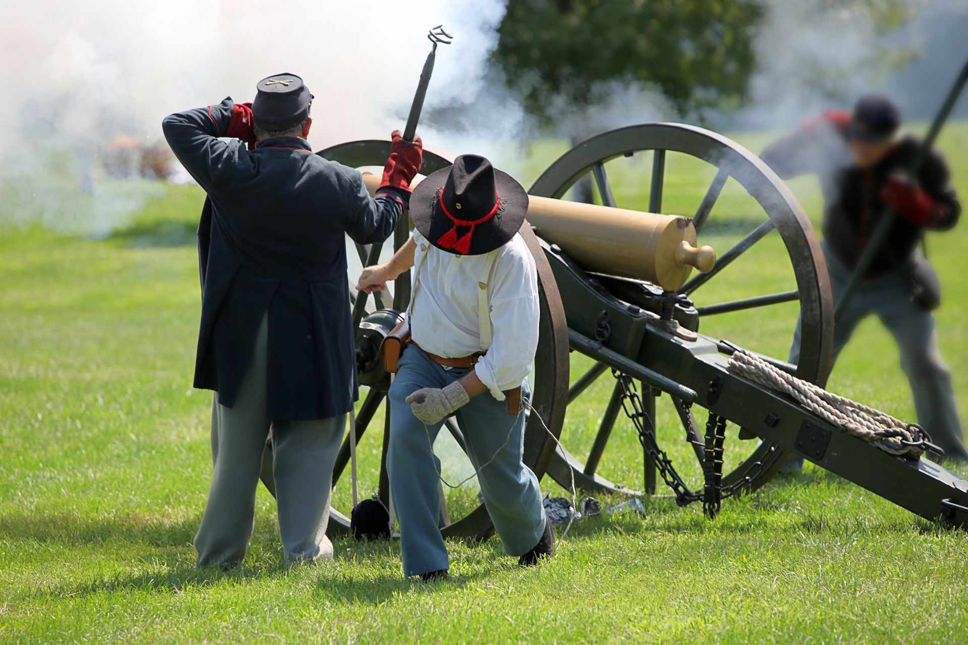A group of men are standing around a cannon in a field.