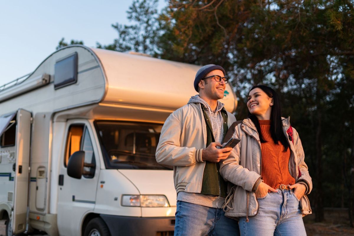 A man and a woman are standing in front of a camper van.