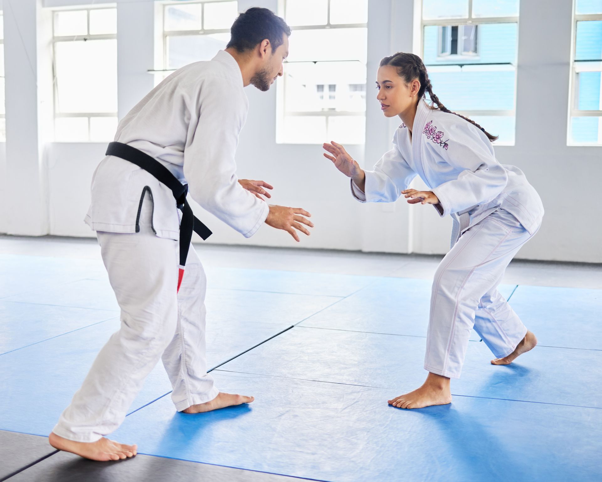 Martial arts instructor and female student sparring in judo or karate dojo class.