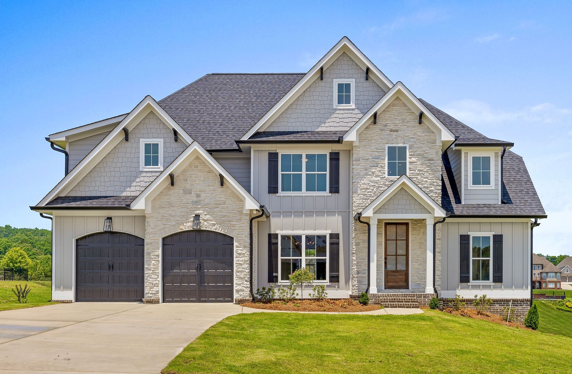 White two-story house with gray roof and accents, surrounded by green grass and trees.