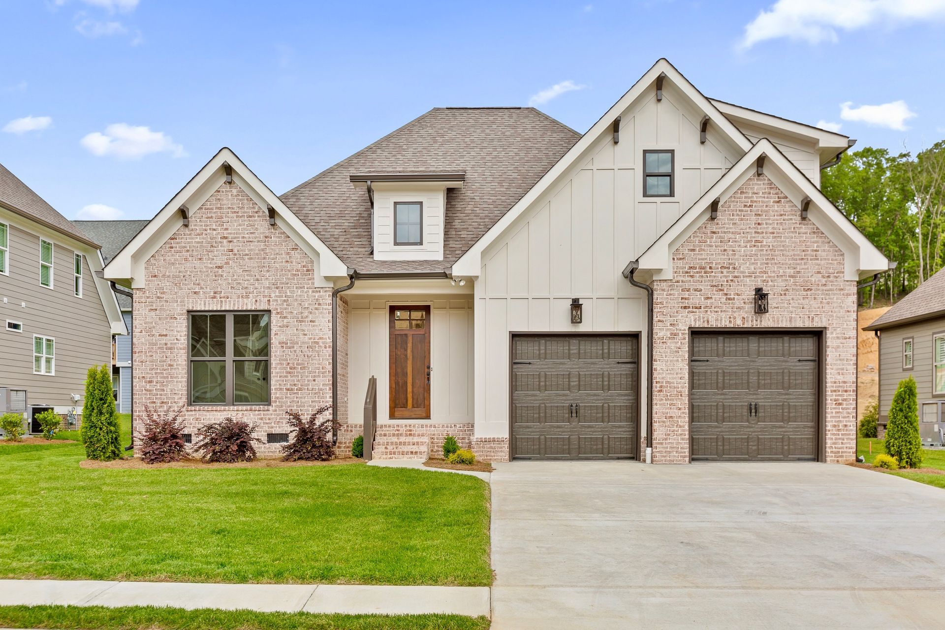 A modern, single-story house with brick accents, two-car garage, and a manicured lawn.
