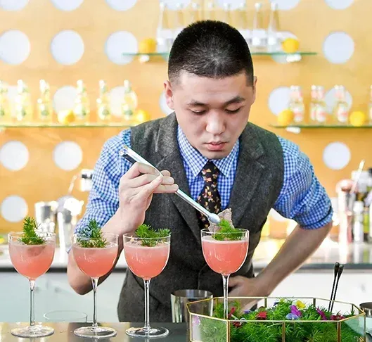 A man in a suit and tie is preparing a drink with a spoon.