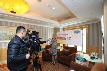A woman is being interviewed by a man and a cameraman in a living room.