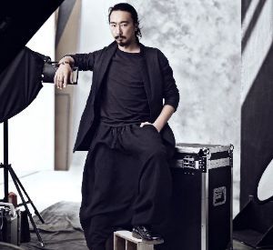 A man in a black suit is sitting on a black case