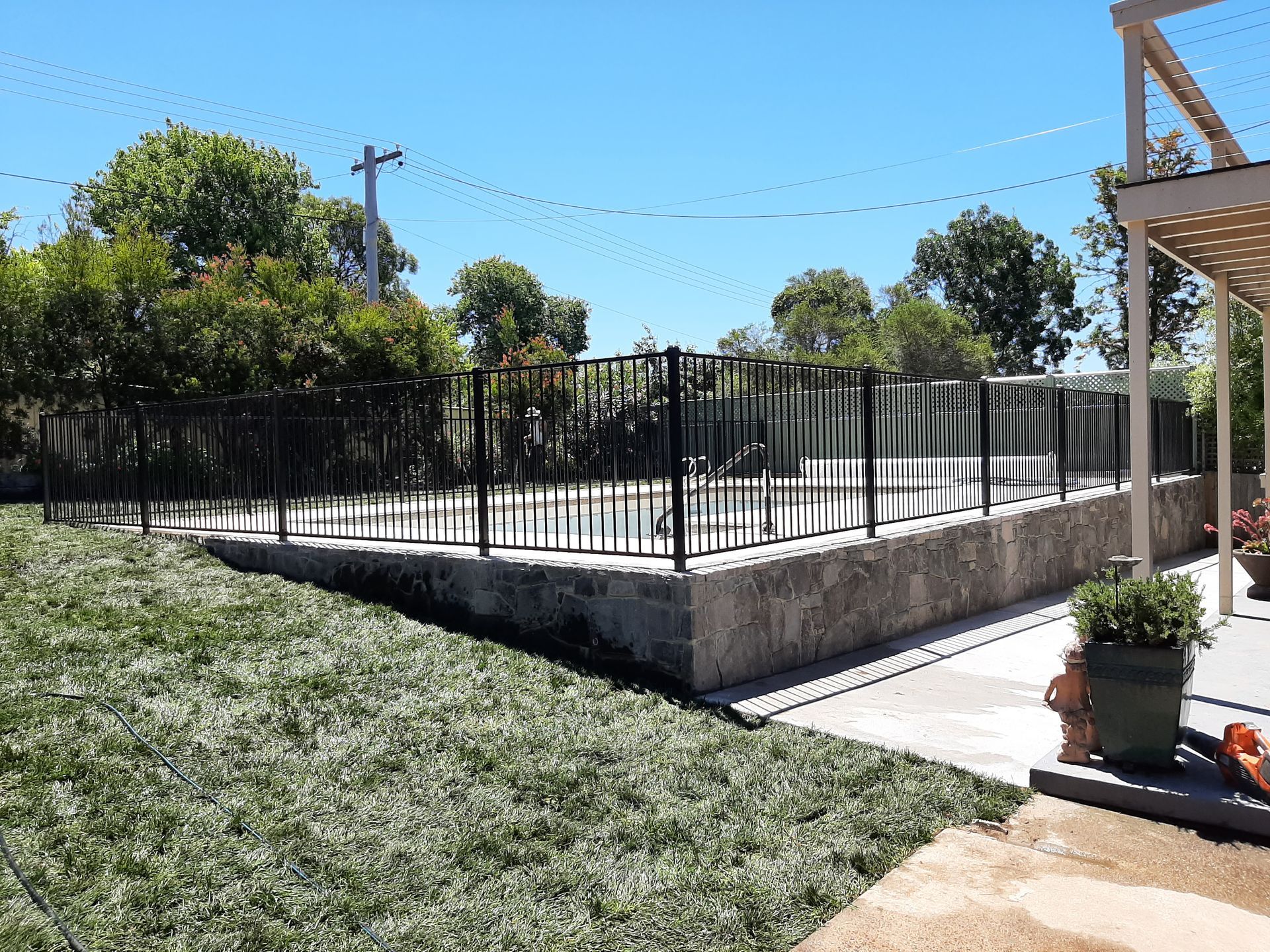 A Large Swimming Pool Is Surrounded by Trees and A Path  — GnB Fencing and Excavation in Queanbeyan, NSW