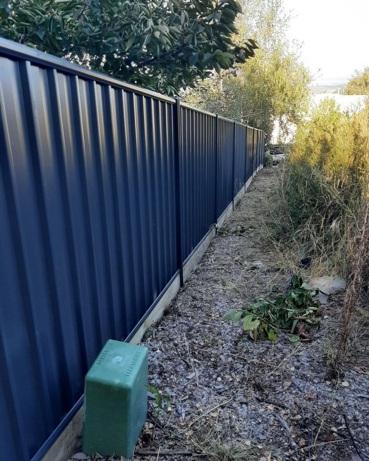 A Backyard with A Black Fence and A House in The Background — GnB Fencing and Excavation in Queanbeyan, NSW