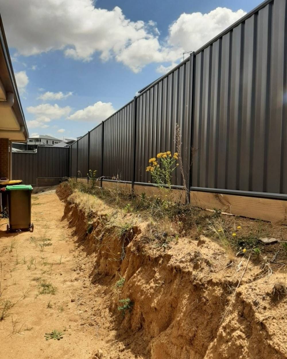 A Black Fence Surrounds a Dirt Area Next to A House  — GnB Fencing and Excavation in Queanbeyan, NSW
