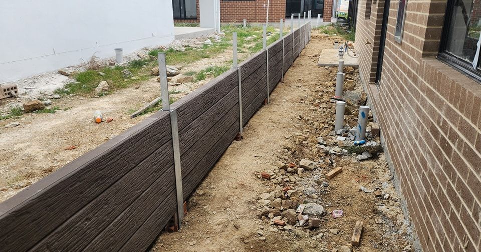A Concrete Wall Is Being Built Next to A Brick Building — GnB Fencing and Excavation in Queanbeyan, NSW
