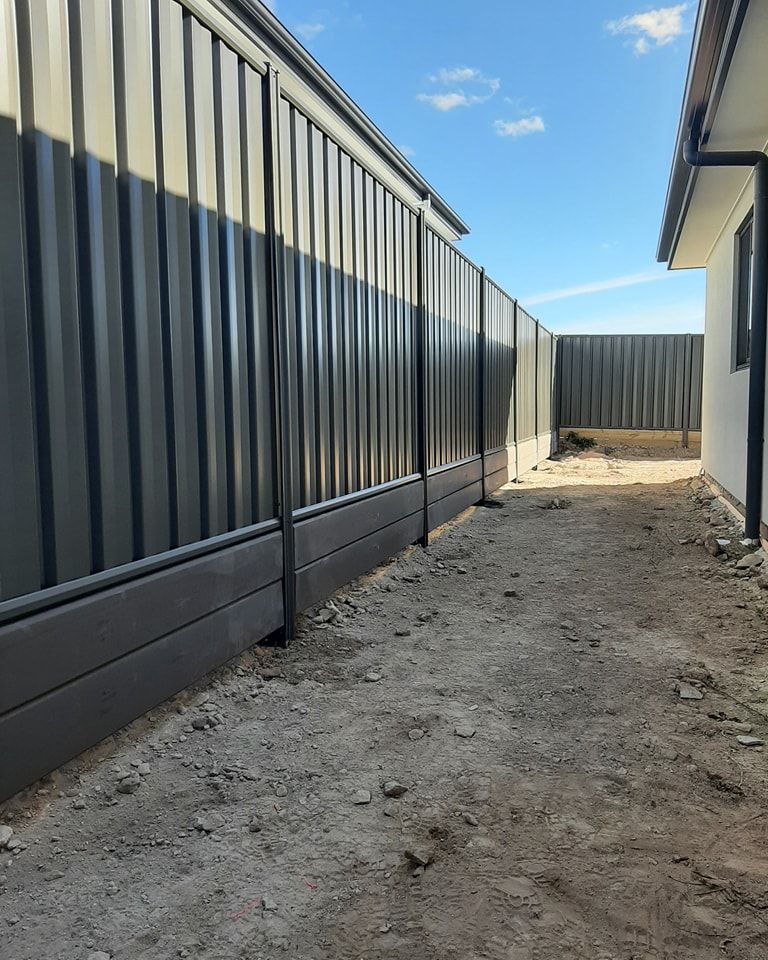 Pathway Between a House and a Tall Metal Fence with Trees and Vegetation Alongside — GnB Fencing and Excavation in Queanbeyan, NSW