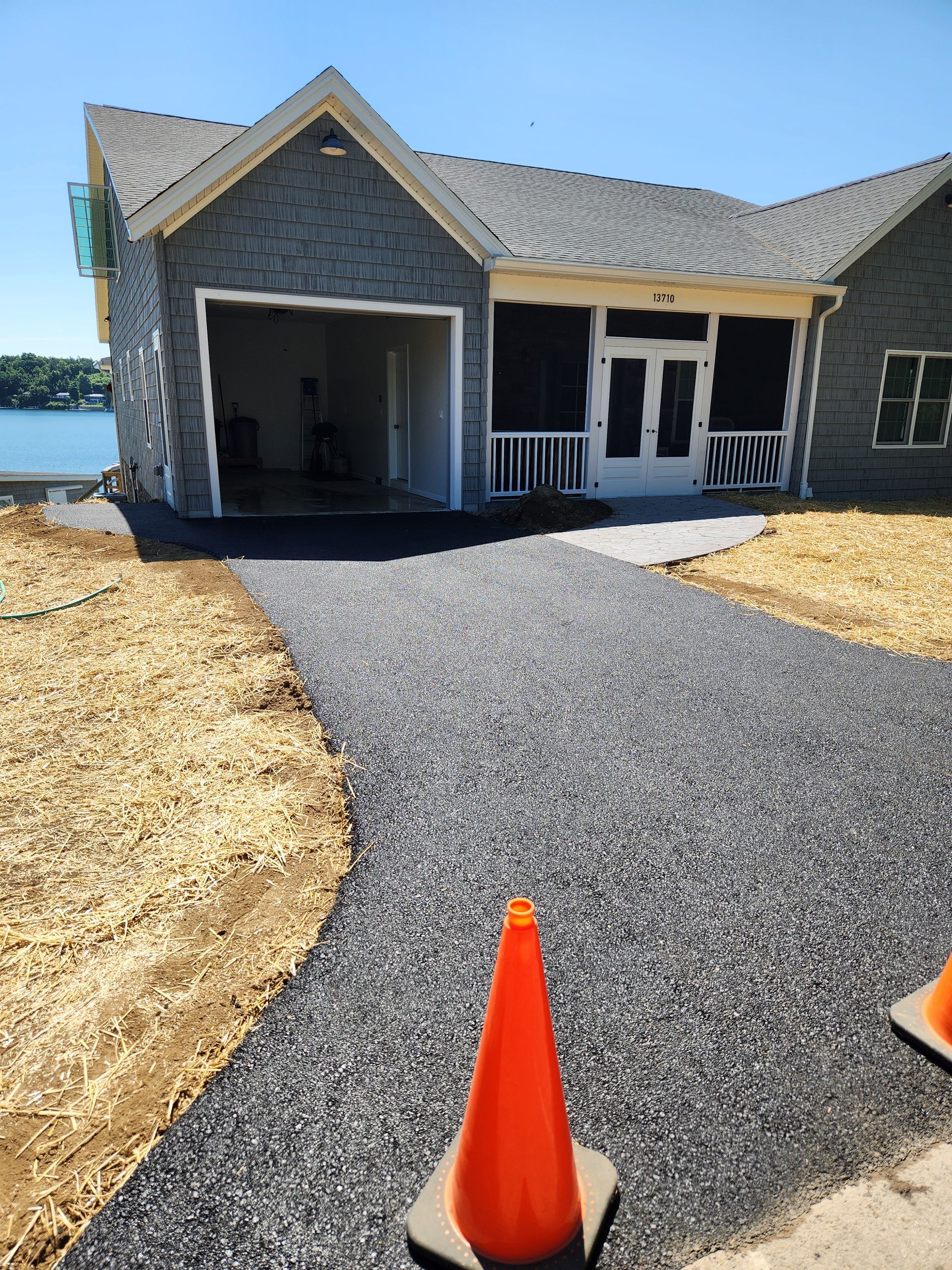 New gravel walkway leading to a gray house porch, marked by orange cones.