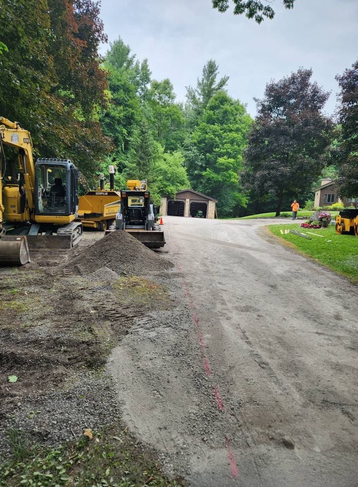 Road construction with excavators and gravel on a tree-lined residential street