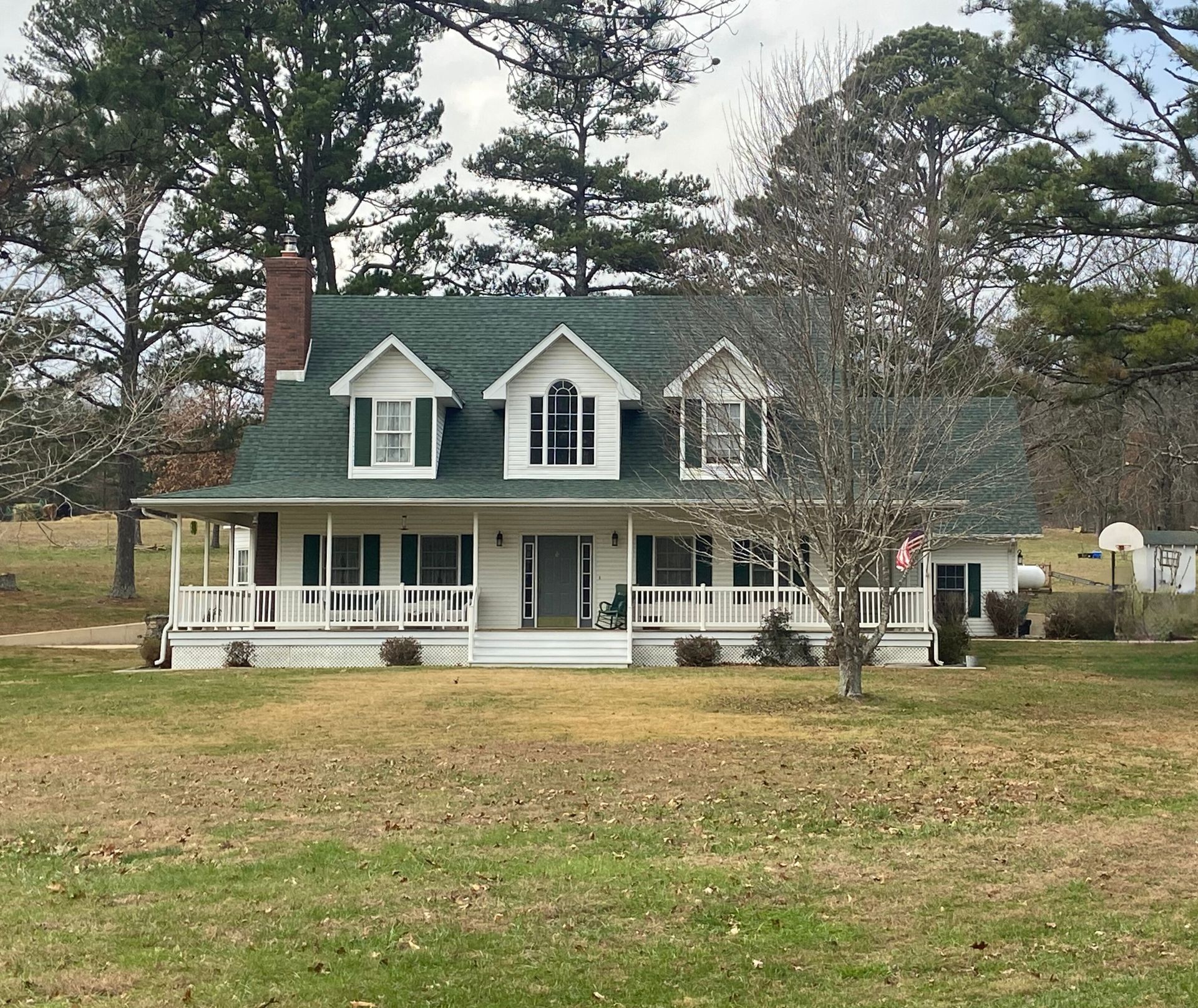 Log cabin with a gray roof, wooden logs, and green lawn.