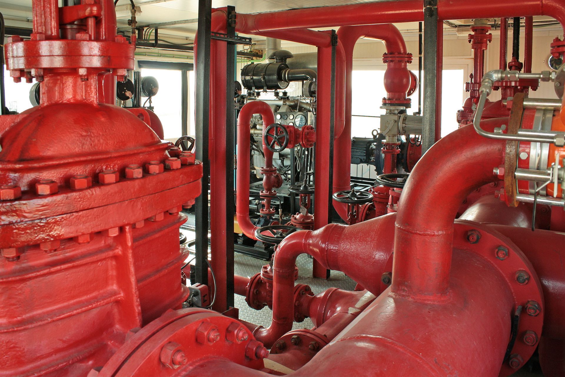 Red pipes and machinery in an industrial setting, likely for fire suppression.
