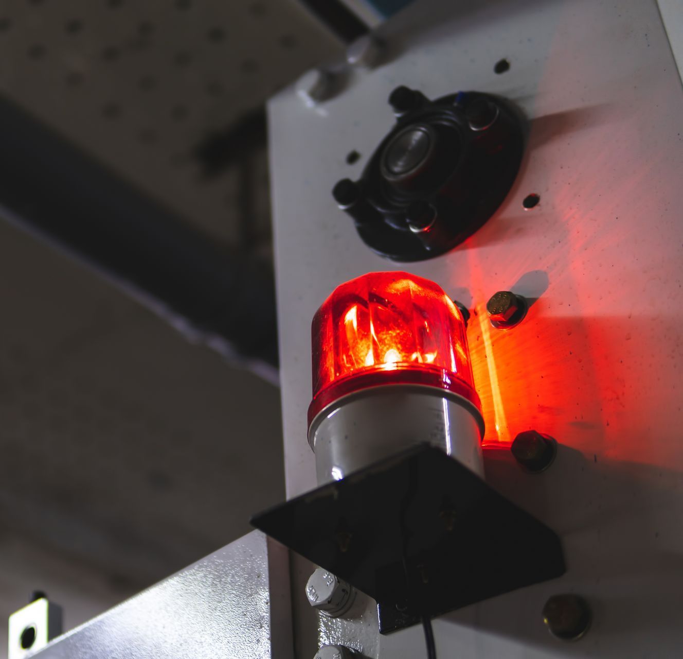 Red warning light on machinery, illuminating a work area.