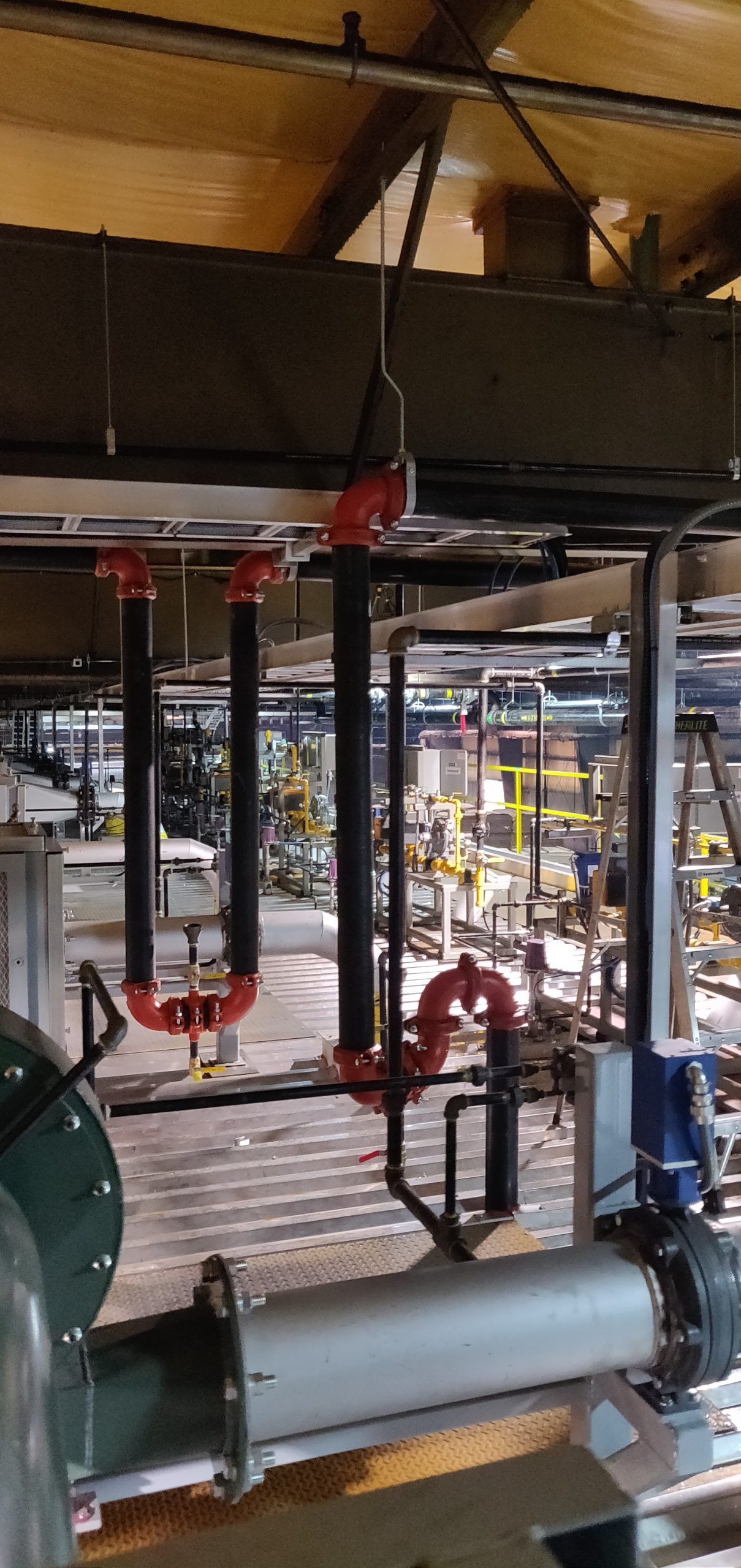 Piping system with red and black pipes, in an industrial setting.