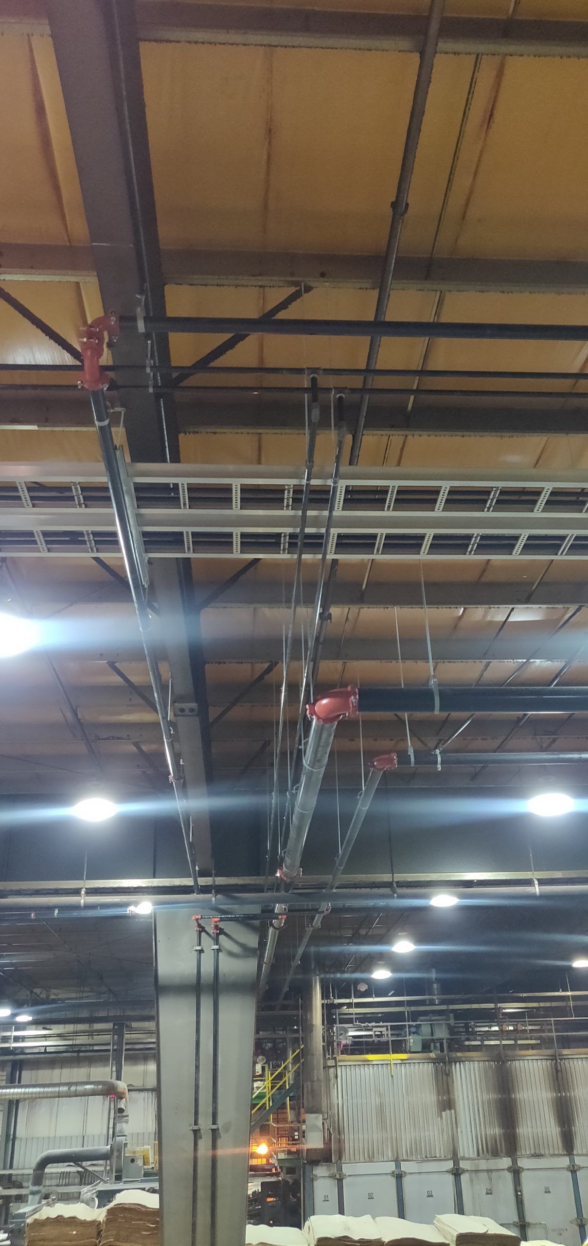 Industrial ceiling with metal beams, electrical conduits, and overhead lighting.