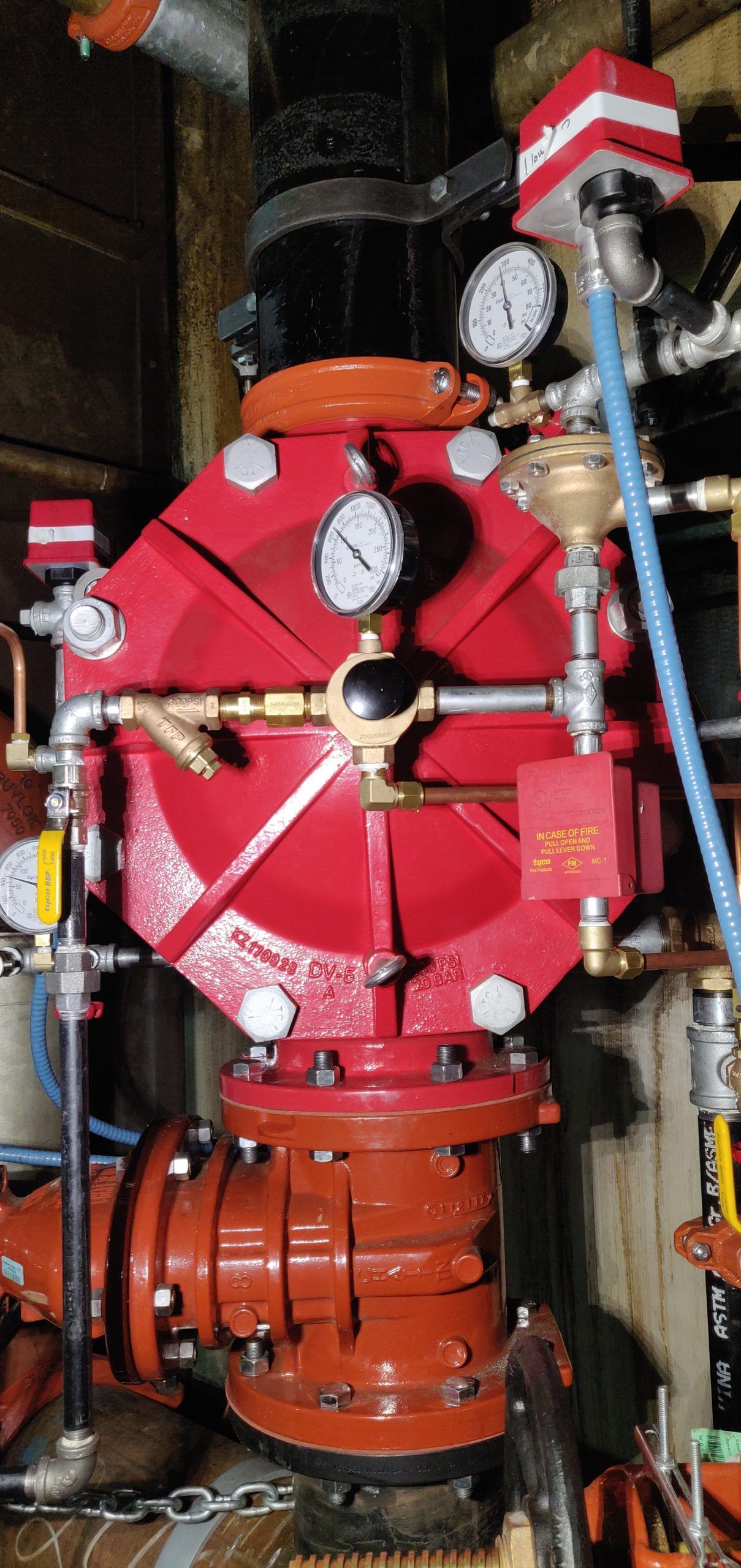 Red fire suppression system valve with gauges and pipes.