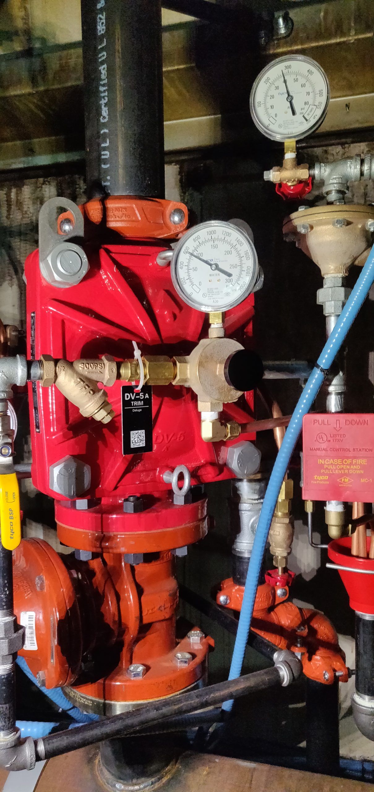Red fire suppression system components with gauges and pipes in an enclosed space.