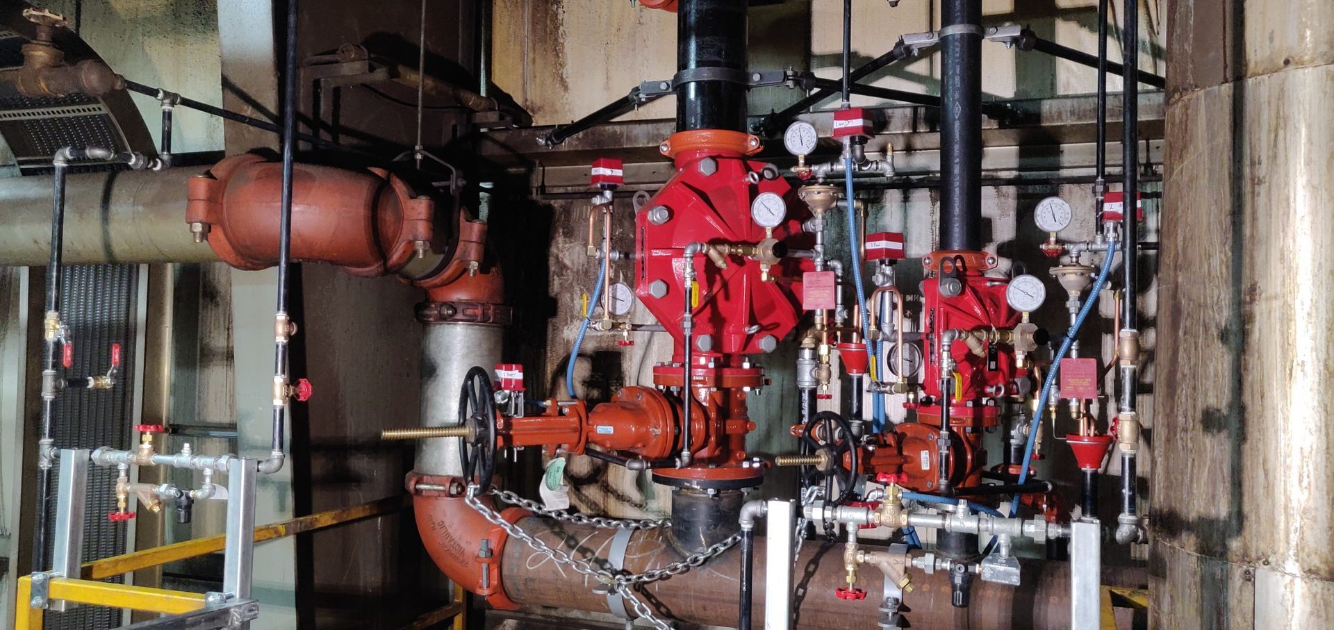 Industrial fire suppression system with red valves and pipes.